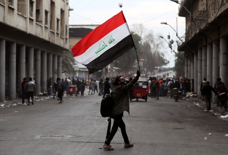 An Iraqi demonstrator carries an Iraqi flag during the ongoing anti-government protests in Baghdad, Iraq November 27, 2019. REUTERS/Thaier al-Sudani