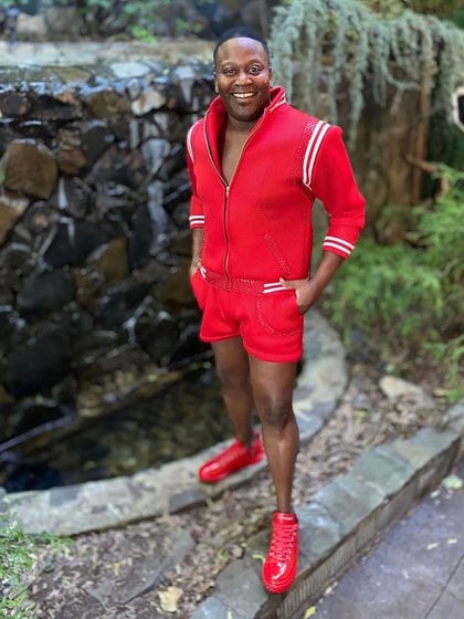 Tituss Burgess para la alfombra roja virtual de los Emmy eligió un total look sporty de campera deportiva y shorts en color rojo, con botines a tono 