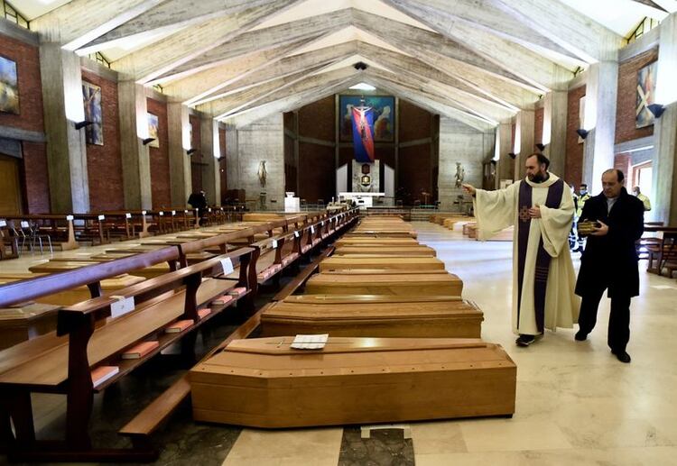 Un sacerdote local bendice los ataúdes almacenados en una iglesia debido al alto número de muertes, antes de que se los lleven los camiones del ejército, mientras Italia lucha por contener la propagación del coronavirus en Seriate, Italia, el 28 de marzo de 2020. REUTERS/Flavio Lo Scalzo