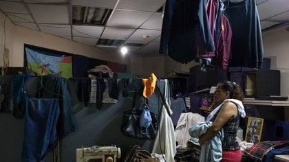Dionicia, 50, picks up her laundry in a room at a shelter located in the basement of the Sudameris public building in Caracas, on October 9, 2020, amid the new coronavirus pandemic. - Fourteen families live without electricity, ventilation, running water or bathrooms in the basement of a government building in Caracas, which makes them specially vulnerable to the coronavirus. (Photo by Cristian Hernandez / AFP)