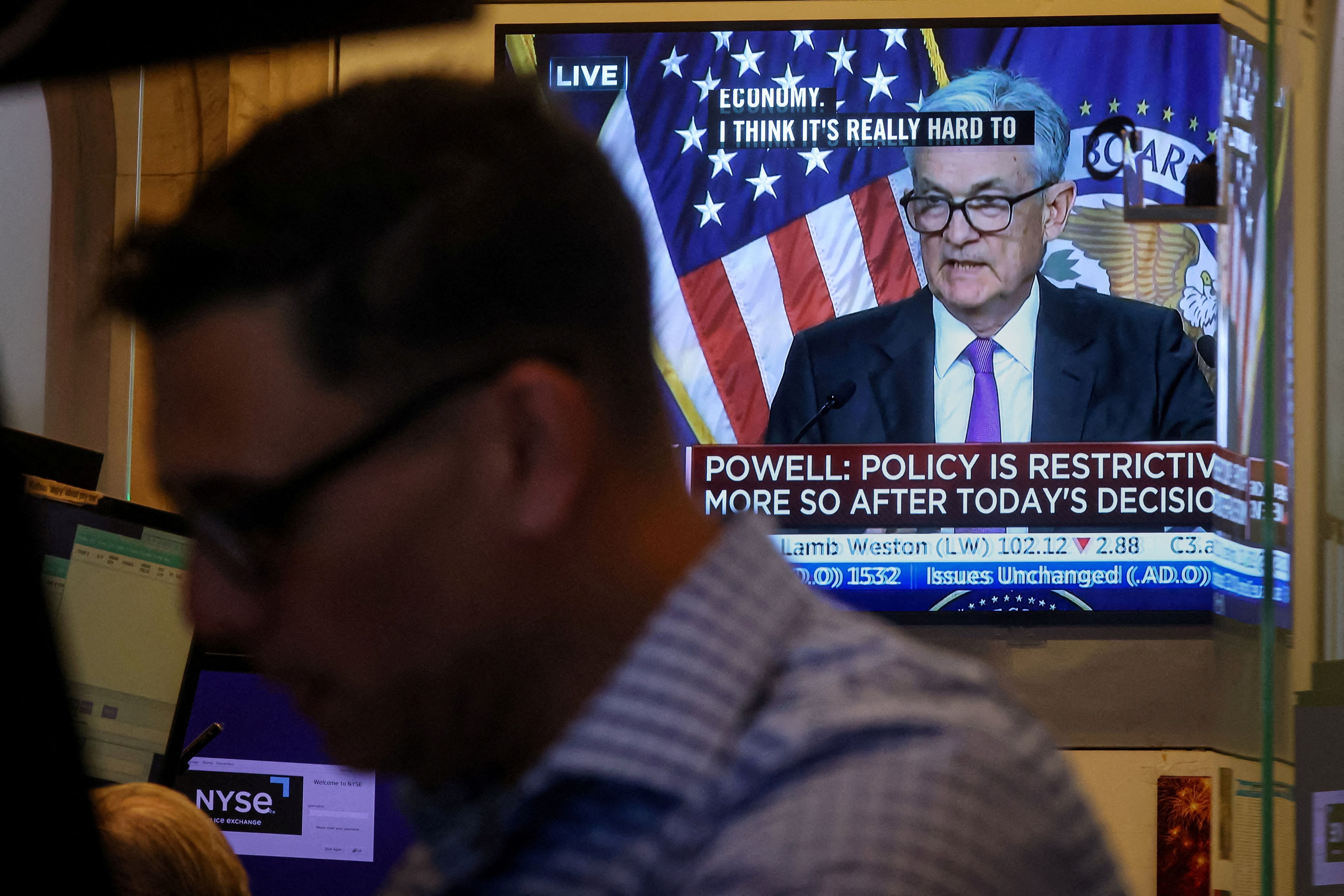 Un operador trabaja, mientras una pantalla muestra una rueda de prensa del presidente de la Reserva Federal, Jerome Powell (REUTERS/Brendan McDermid)