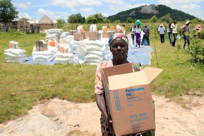 Vecinos de un pueblo rural de Zimbabwe recogen una caja de alimentos del programa en Mudzi (REUTERS/Philimon Bulawayo)