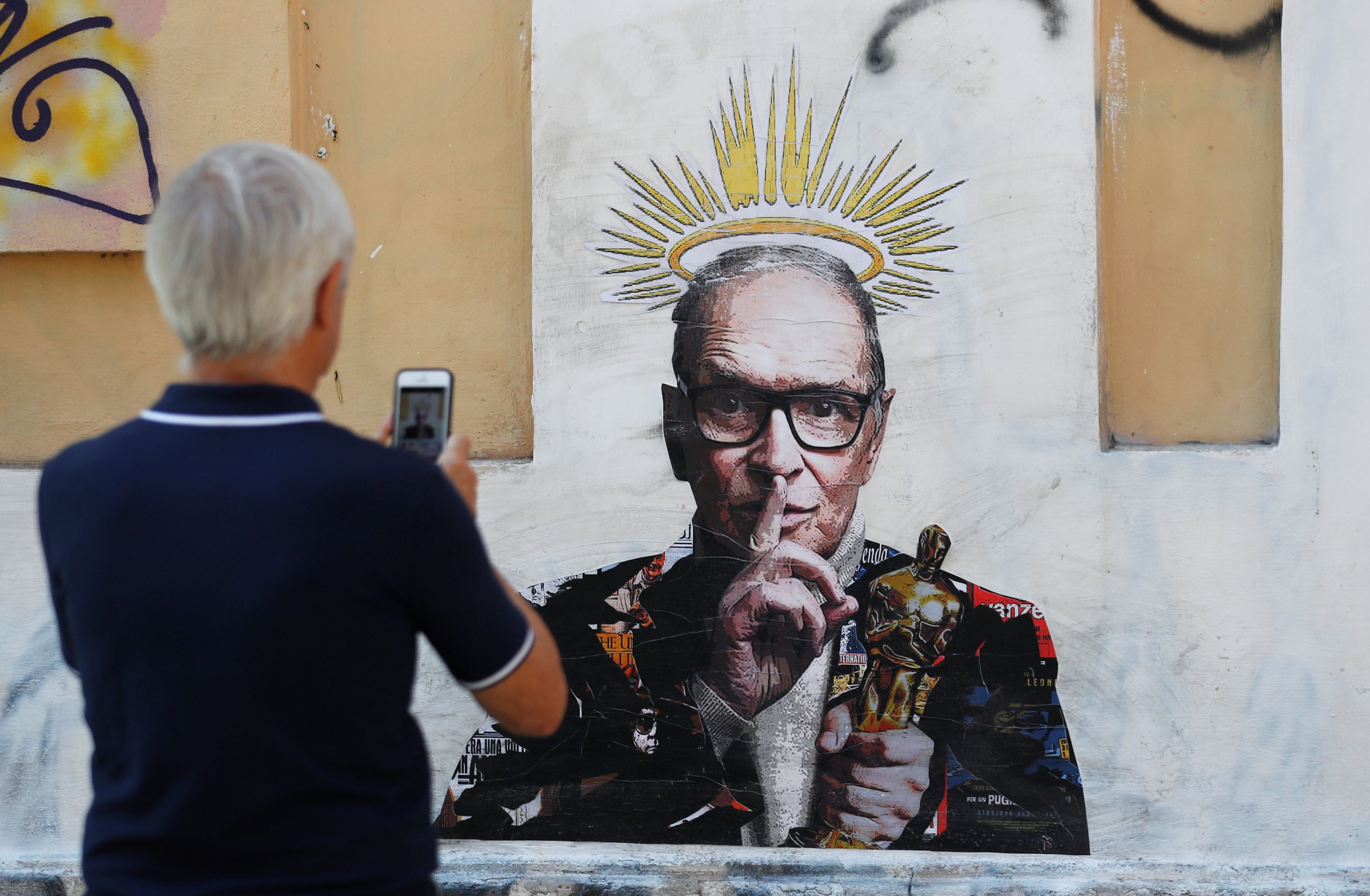 Un hombre toma una fotografía de un mural dedicado al compositor italiano Ennio Morricone, quien murió a la edad de 91 años, en 2020 (REUTERS/Yara Nardi)
