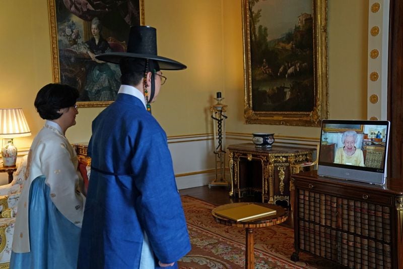La reina Isabel de Gran Bretaña aparece en una pantalla a través de un enlace de video desde el castillo de Windsor, donde reside, durante una audiencia virtual para recibir al embajador de la República de Corea, Gunn Kim, acompañado por HeeJung Lee, en el Palacio de Buckingham, Londres, Gran Bretaña, 26 octubre 2021.Victoria Jones/Pool vía REUTERS