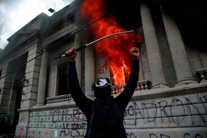 Un hombre protesta en frente del Congreso de Guatemala en llamas ocasionado por manifestantes que protestan contra del Gobierno del presidente, Alejandro Giammattei hoy en Ciudad de G. EFE/Esteban Biba
