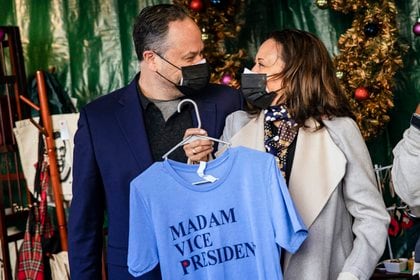 FILE -- Vice President-elect Kamala Harris and her husband, Doug Emhoff, hold up a t-shirt that says “Madam Vice President” while visiting small businesses at a holiday market on Small Business Saturday in Washington, on Nov. 28, 2020. What’s it like to have Kamala Harris as ‘Momala’? Her stepkids Cole and Ella Emhoff weigh in.  (Samuel Corum/The New York Times)
