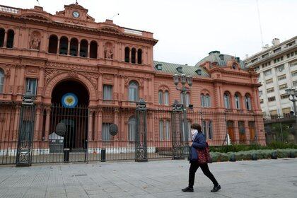 Una mujer camina frente al palacio presidencial Casa Rosada, en Buenos Aires, Argentina el 21 de mayo - Agustin Marcarian