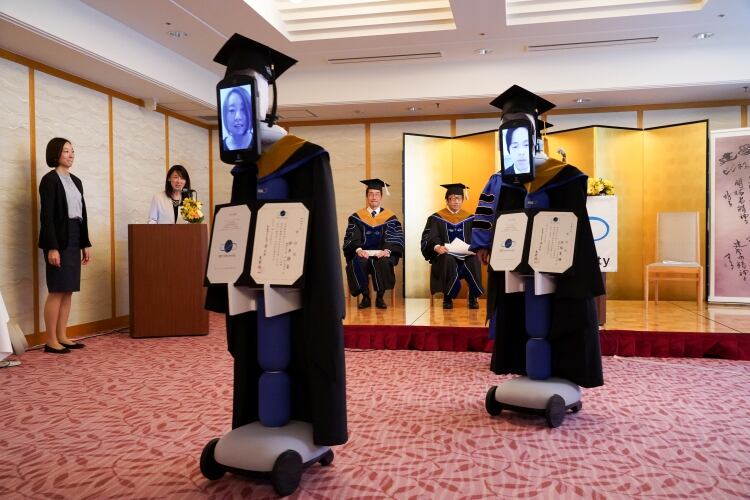 Cuando se mencionaba el nombre del graduado, el robot que lo representaba se acercaba al presidente de la universidad, Omae Kenichi, que estaba en el escenario, para recibir el diploma. (BBT UNIVERSITY/Handout via REUTERS)