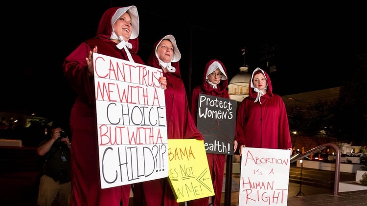 Las activistas Bianca Cameron-Schwiesow, Kari Crowe, Allie Curlette y Margeaux Hartline, vestidas como las protagonistas de “El cuento de la criada”, protestan frente al legislativo de Alabama tras la aprobación de una ley que establece una prohibición casi total del aborto (Reuters)