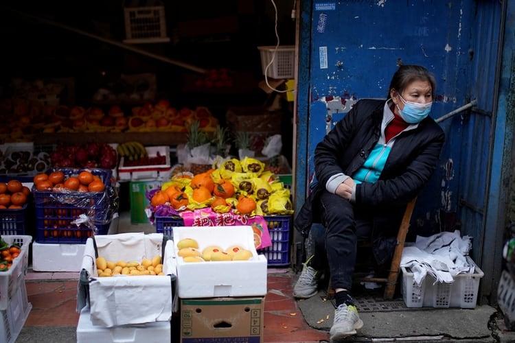 A woman wearing a face mask sits next to a fruit stall at a residential area after the lockdown was lifted in Wuhan, capital of Hubei province and China's epicentre of the novel coronavirus disease (COVID-19) outbreak, April 11, 2020. REUTERS/Aly Song
