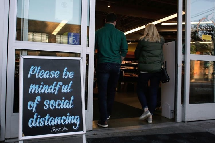 Los compradores entran en una tienda de comestibles ante un cartel que solicita el distanciamiento social, tras los informes de casos de enfermedad coronavirus (COVID-19) en la zona, en Seattle, Washington, EEUU 17 de marzo de 2020. REUTERS/David Ryder