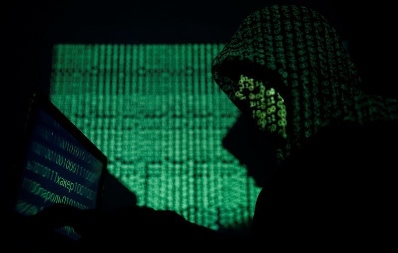 Persona encapuchada sostiene una computadora portátil mientras se proyecta el código cibernético sobre él en esta imagen ilustrativa tomada 13 mayo 2017.
REUTERS/Kacper Pempel/