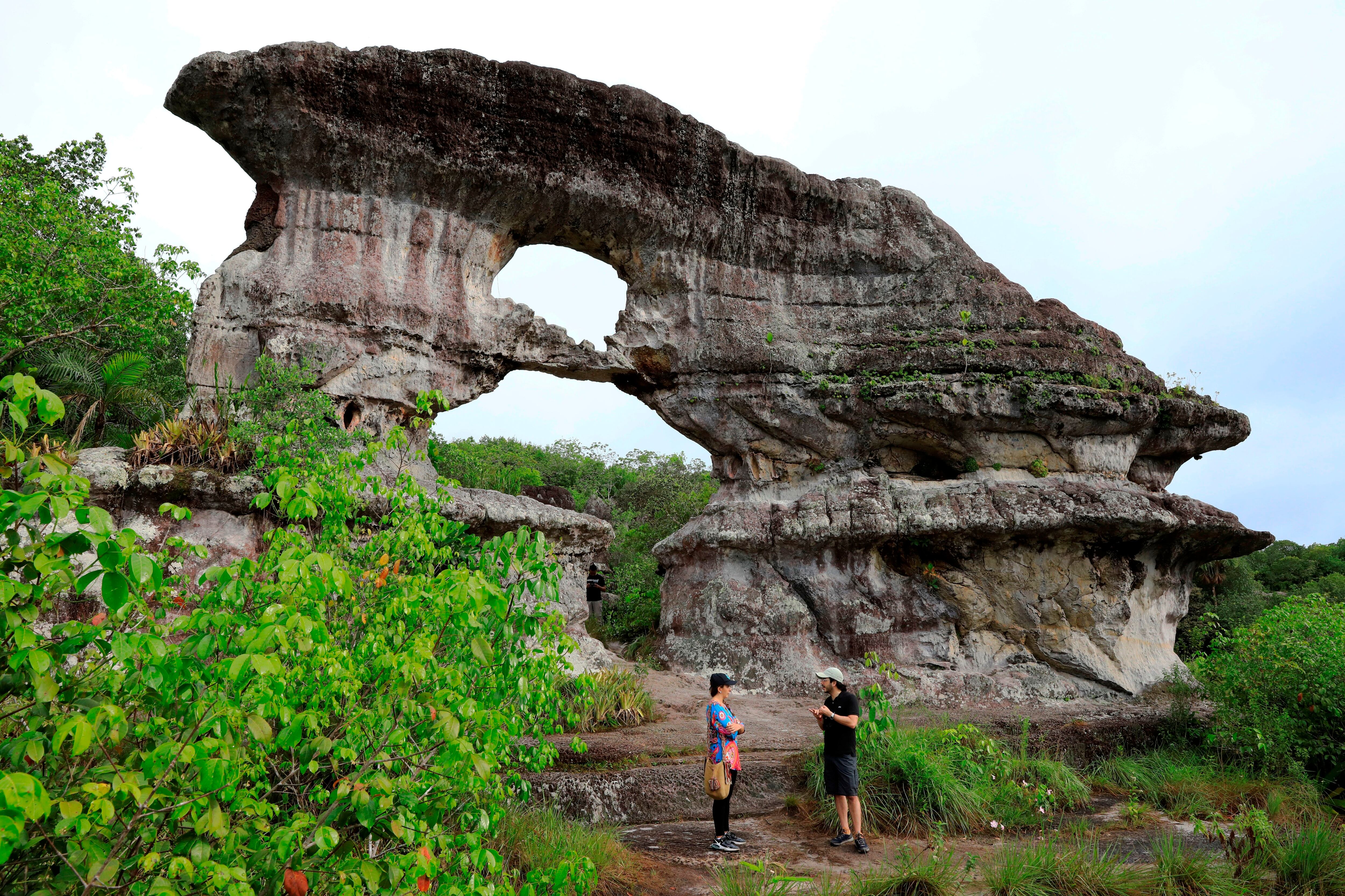 Fotografía del 30 de septiembre de 2021 que muestra a un grupo de visitantes que recorre la Puerta de Orión, una formación rocosa en zona rural de San José de Guaviare (Colombia). EFE/Carlos Ortega