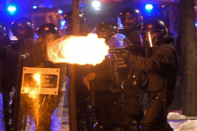 Un policía dispara a la multitud que protestó anoche (LLUIS GENE/ AFP)
