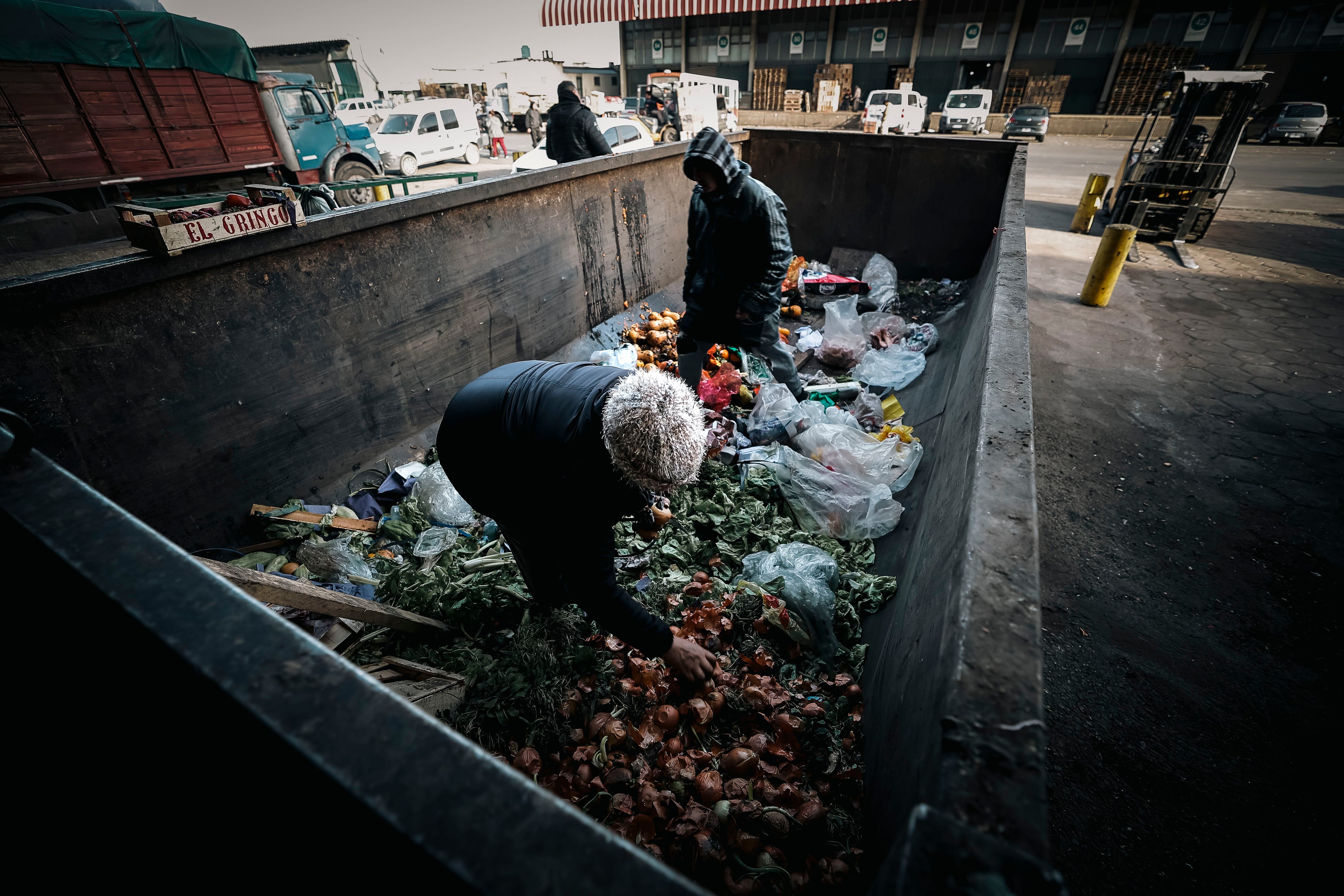 Fotografía de archivo, tomada el 8 de agosto de 2023, en la que se registró a un par de personas al buscar comida, entre un contenedor de residuos de una de central de abastos, en un barrio de la periferia de Buenos Aires (Argentina). EFE/Juan Ignacio Roncoroni 
