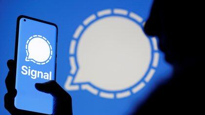 A woman holds a smartphone displaying the Signal messaging app logo, which is also seen near her, in this illustration taken January 13, 2021. REUTERS/Dado Ruvic