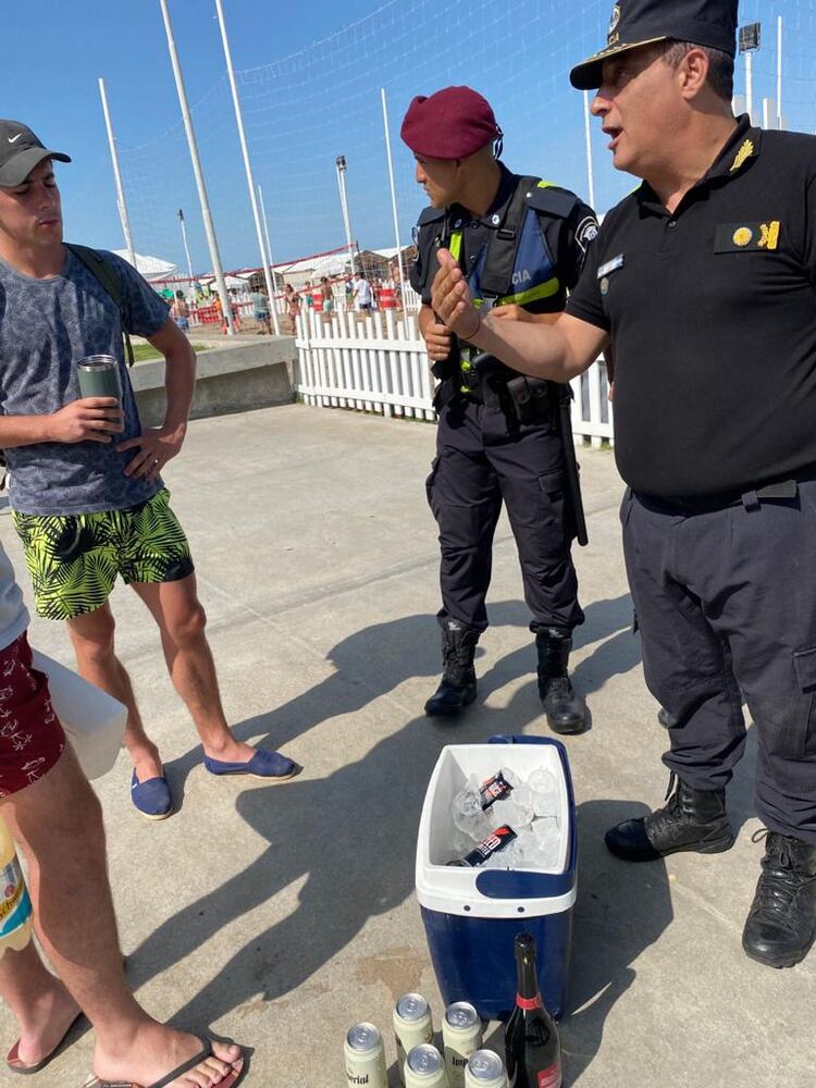 La policía les explica a un grupo de adolescentes recién llegados a la playa que no podrán ingresar con bebidas alcoholicas