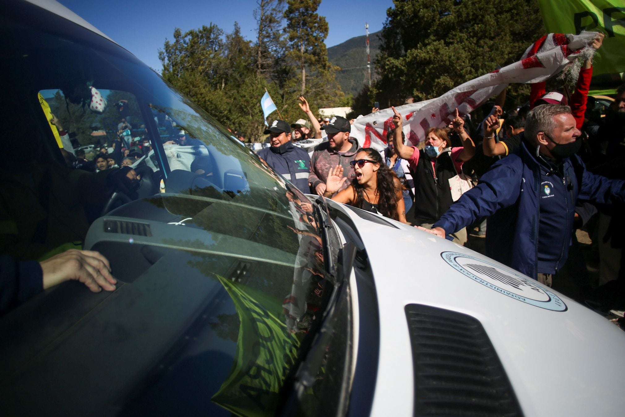 Demonstrators shout slogans to the van in which Argentina's President Alberto Fernandez is transported in Lago Puelo, to monitor the lands that were ravaged by fires, in the province of Chubut, Argentina March 13, 2021. REUTERS/Matias Garay  NO RESALES. NO ARCHIVES