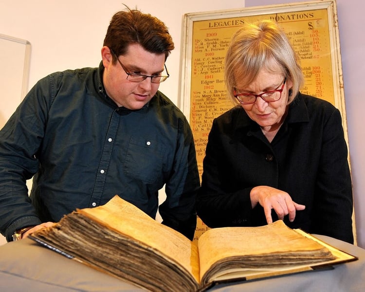 Los investigadores Sarah Rees Jonesy Gary Brannan observan los registros del arzobispo William Melton (University of York)