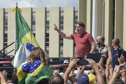 Bolsonaro habla tras unirse a sus partidarios en una caravana para protestar contra las medidas de cuarentena y distanciamiento social en Brasilia el 19 de abril de 2020. (Foto de EVARISTO SA / AFP)