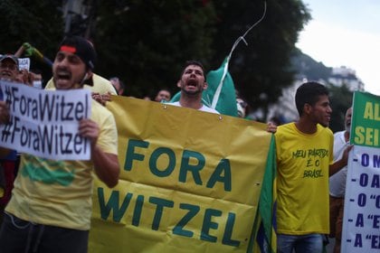 Personas muestran carteles pidiendo la salida de Witzel de su cargo. Foto: REUTERS/Pilar Olivares