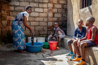 Tresor Ndizihiwe, de 12 años (centro), ayuda a lavar la ropa a su madre, Jacqueline Mukantwari (izquierda), junto a sus hermanos, en su casa en Kigali, Ruanda. Mukantwari recibía un salario de 50 dólares mensuales como maestra de escuela, pero solía ganar dinero extra al dar clases privadas. Ese negocio se ha terminado  (AP Foto)
