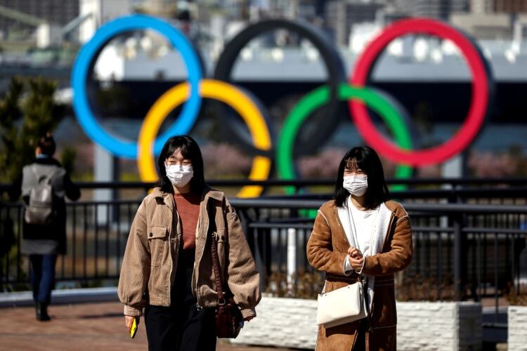 Dos mujeres con barbijos en Tokio. Detrás se observa el símbolo de los Juegos Olímpicos (REUTERS/Athit Perawongmetha)