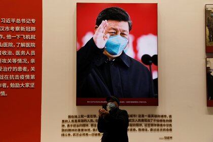 Un visitante se para cerca de una imagen del jefe del régimen chino Xi Jinping durante una exposición sobre la lucha contra el brote del coronavirus en el Centro de Convenciones del Salón de Wuhan (Reuters)