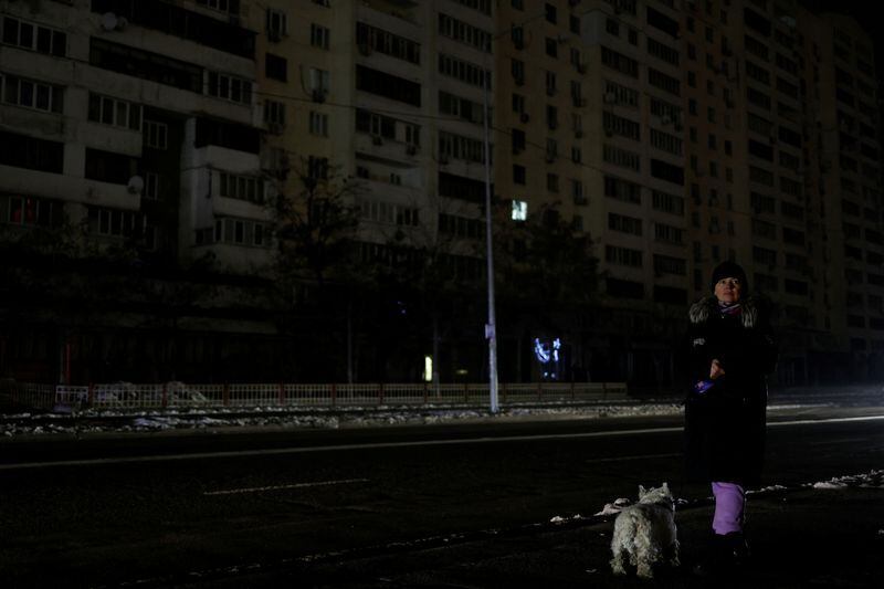 Foto de archivo: Una mujer con un perro espera un autobús en una calle sin electricidad después de que la infraestructura civil crítica fuera alcanzada por los ataques de misiles rusos en Kiev, Ucrania, el 23 de noviembre de 2022 (REUTERS/Valentyn Ogirenko)