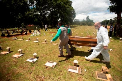 Trabajadores cargan un féretro con una víctima mortal de covid-19 rumbo a su entierro en el cementerio Campo da Esperança, en Brasilia (Brasil). EFE/ Joédson Alves


