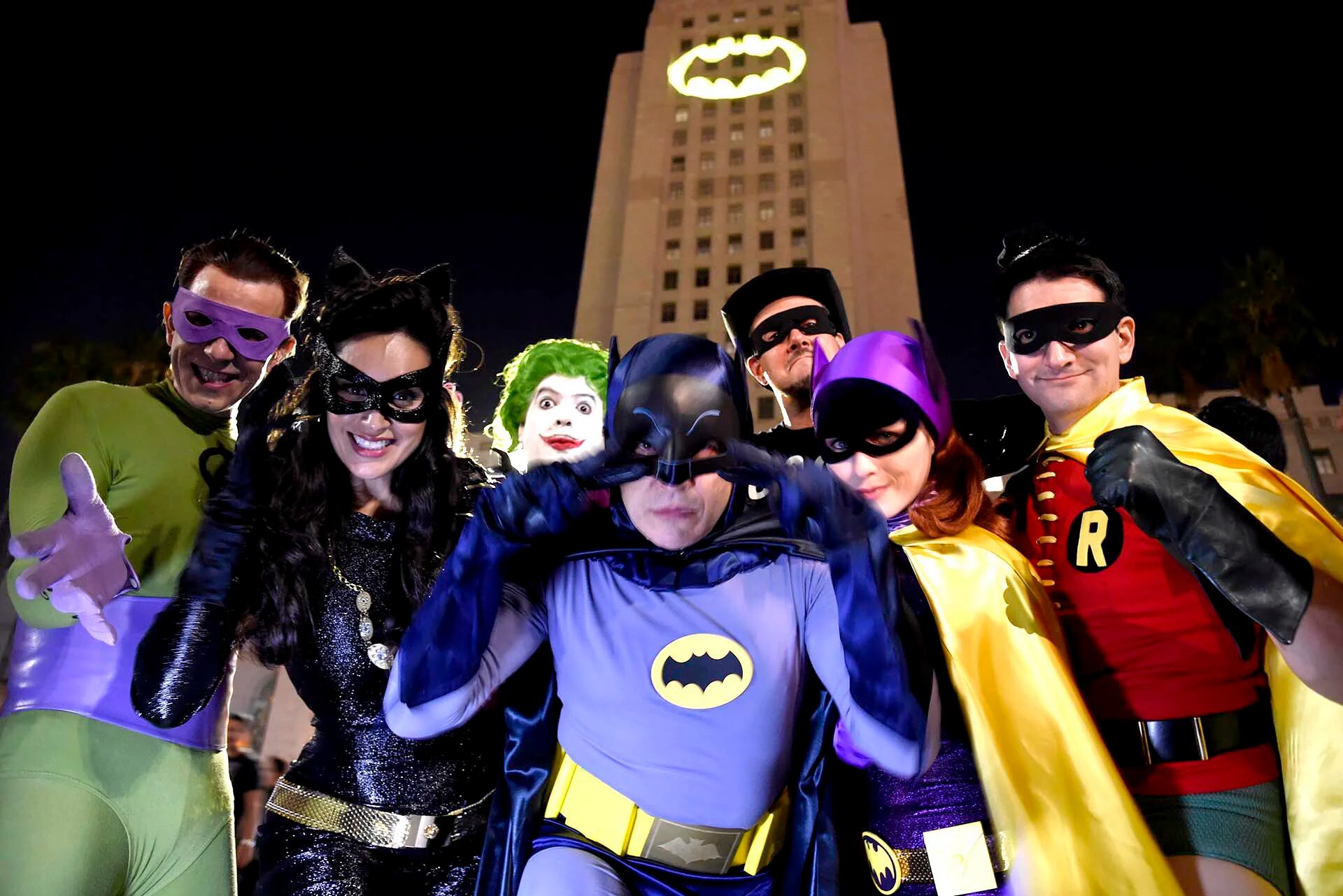 Fanáticos de Batman vestidos como los personajes de la serie frente a una “Batiseñal” proyectada en el Ayuntamiento de Los Ángeles durante un homenaje al fallecido actor Adam West