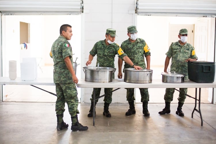 Soldados mexicanos preparaban el almuerzo de un grupo de migrantes alojados en un refugio abierto recientemente en Ciudad Juárez. (Celia Talbot Tobin/The New York Times)