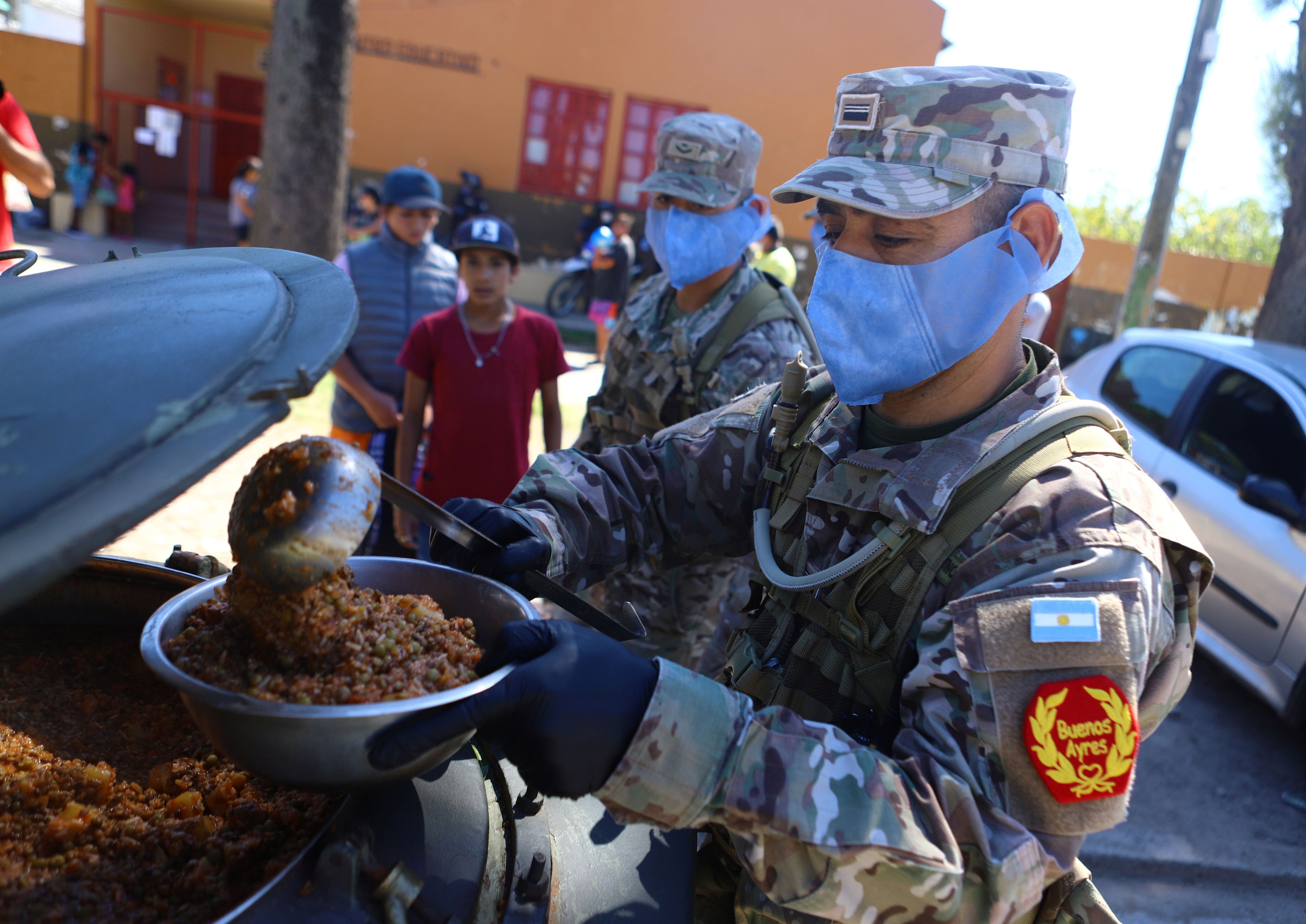 Military staff wearing protective masks serve a ration of food aid, organized by the municipality for a low-income neighborhood, during the mandatory quarantine for coronavirus disease (COVID-19), in Quilmes, on the outskirts of Buenos Aires, Argentina March 23, 2020