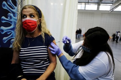 Una mujer recibe una vacuna contra la enfermedad del coronavirus (COVID-19) en un centro temporal de la organización de mantenimiento de la salud (HMO) Clalit, en una cancha de baloncesto en Petah Tikva