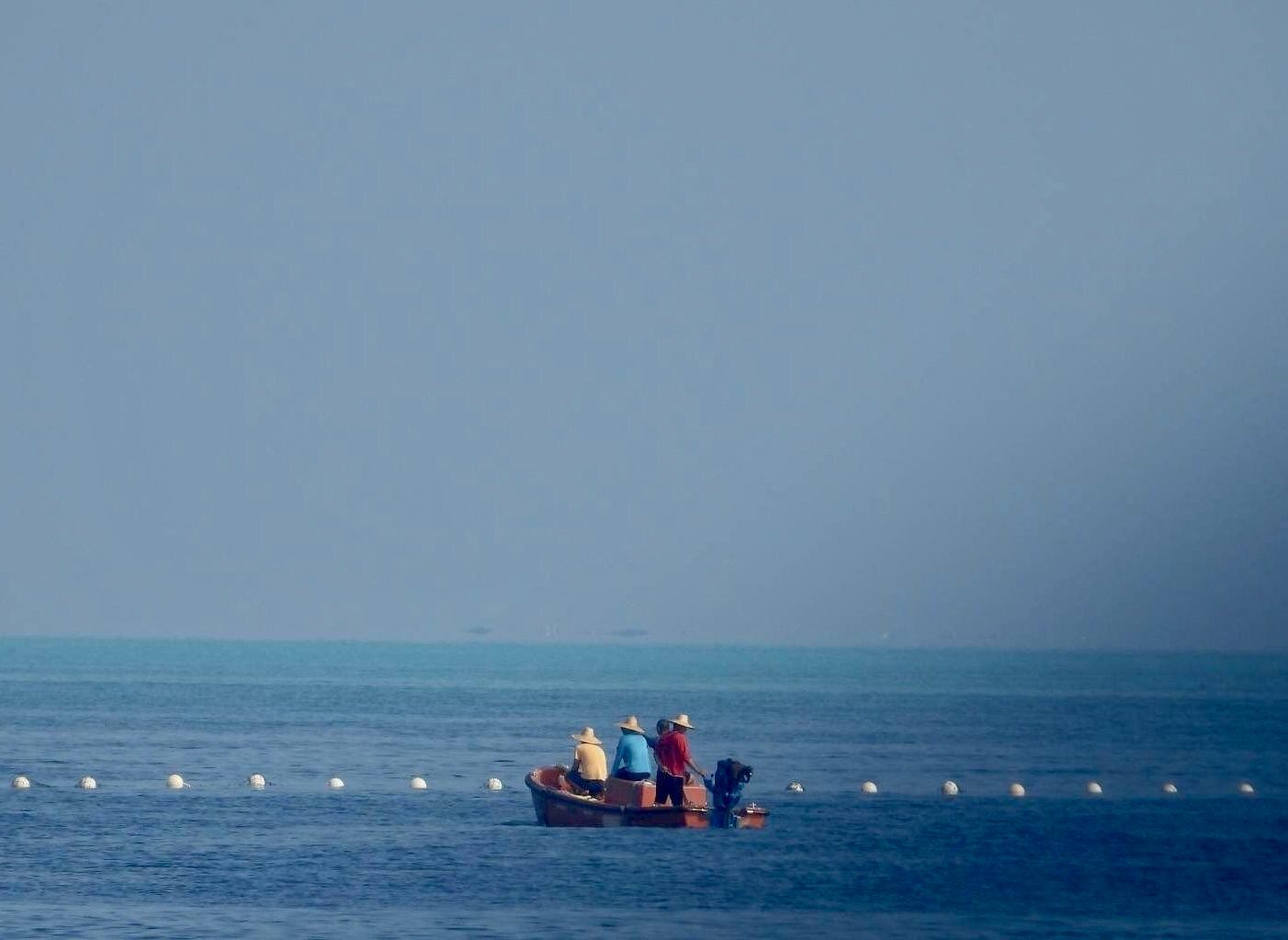 Pescadores cerca de la barrera flotante (EFE)