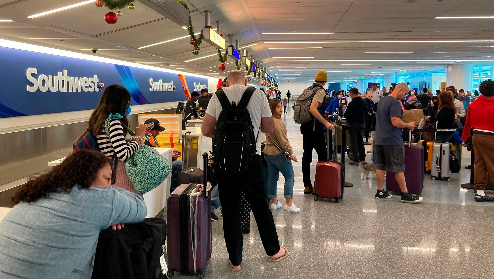 Travelers wait at a Southwest Airlines baggage counter to retrieve their bags after canceled flights at Los Angeles International Airport, Monday, Dec. 26, 2022, in Los Angeles. (AP Photo/Eugene Garcia)
