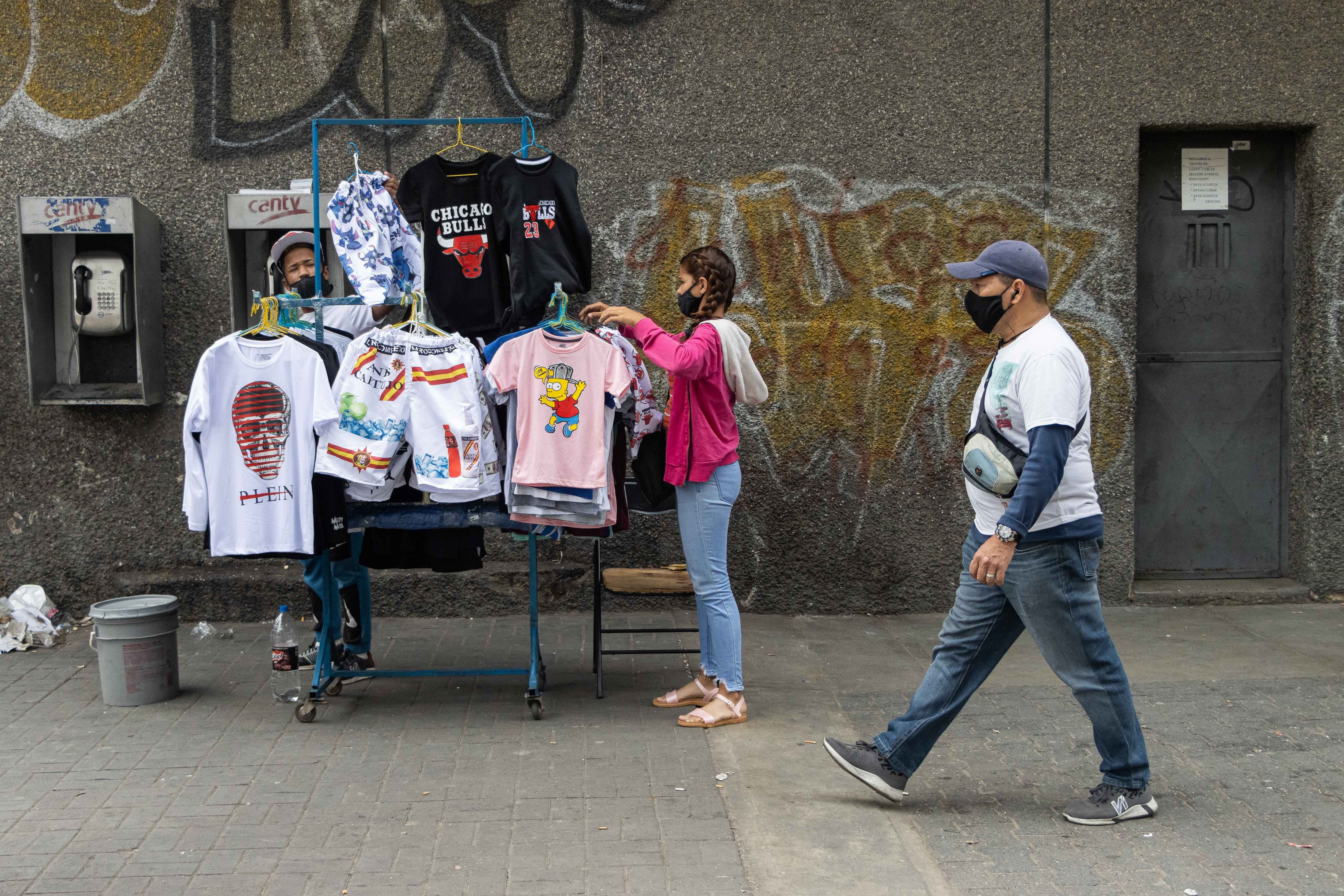 Una mujer ordena las camisas que vende en el mercado de Catia en Caracas (EFE/Ronald Peña/Archivo)