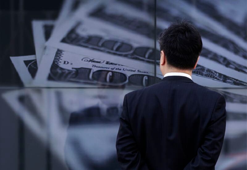 FOTO DE ARCHIVO: Un hombre de negocios mira una pantalla que muestra una foto de billetes de 100 dólares estadounidenses en Tokio. 8 de abril de 2013. REUTERS/Toru Hanai