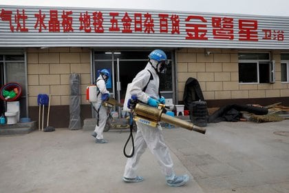 Voluntarios del equipo de rescate Blue Sky, con trajes protectores, desinfectan el mercado integral de Nangong, en Pekín, China, el 18 de junio de 2020. Foto tomada el 18 de junio de 2020. REUTERS/Carlos Garica Rawlins