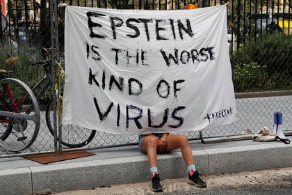 Una manifestante se sienta con un cartel que dice "Epstein es la peor clase de virus" frente al Tribunal Federal de Manhattan el 14 de julio de 2020, durante la audiencia de acusación de Ghislaine Maxwell por su papel en la prostitución de niñas menores por parte del financista fallecido (REUTERS/Mike Segar)