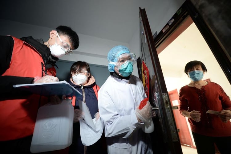 Trabajadores comunitarios y personal médico visitan a una mujer en su casa mientras realizan una búsqueda puerta a puerta para inspeccionar a los residentes para saber si hay algún nuevo caso de coronavirus en China (Reuters)