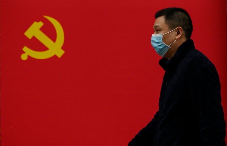 Un hombre pasa frente a una bandera del Partido Comunista en una calle de Wuhan (NOEL CELIS / AFP)