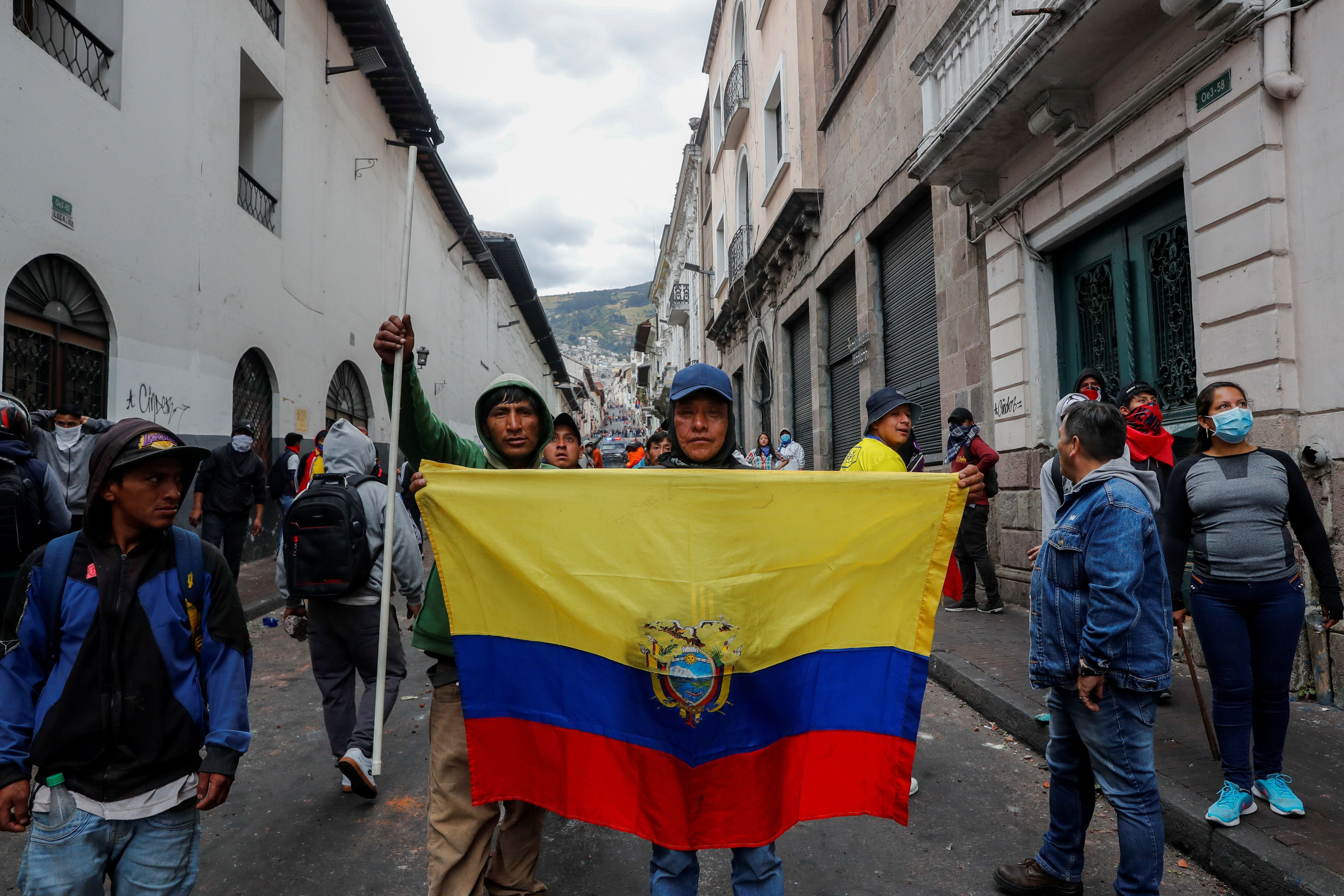 Un manifestante cubierto con una bandera ecuatoriana se para frente a un vehículo blindado durante una protesta contra las medidas de austeridad del presidente de Ecuador, Lenín Moreno, en Quito, Ecuador, el 9 de octubre de 2019. (REUTERS/Ivan Alvarado)
