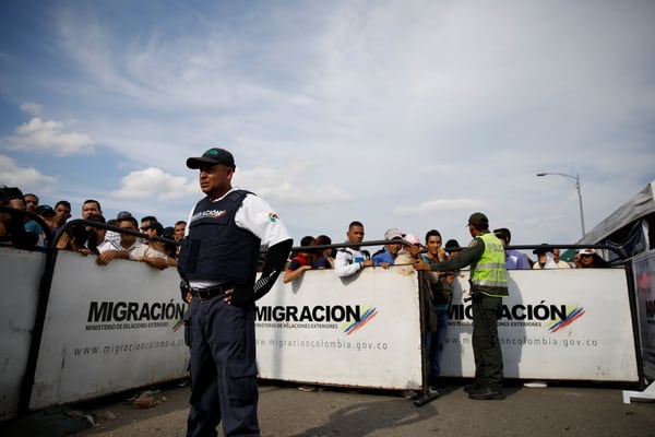 Un oficial de migraciones supervisa las largas filas en un paso fronterizo (Reuters)