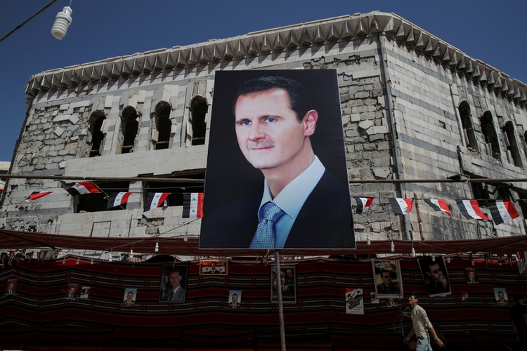 Un hombre pasa junto a una pancarta con el rostro del dictador sirio Bashar al Assad en Douma, en las afueras de Damasco, Siria, el 17 de septiembre de 2018 (REUTERS/Marko Djurica/File Photo)