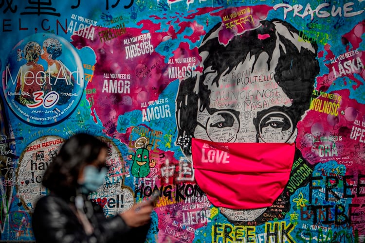 Una persona con barbijo pasa frente al muro dedicado a John Lennon, que ahora también tiene un barbijo, en Praga, República Checha, el 6 de abril de 2020 (EFE/EPA/MARTIN DIVISEK)