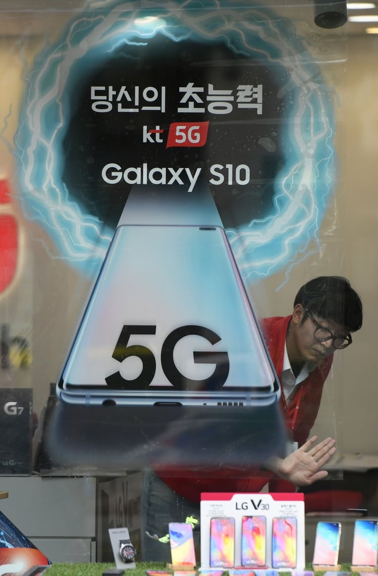 Un empleado prepara un anuncio para el servicio de redes móviles 5G de KT en una tienda de telecomunicaciones en Seúl el 4 de abril de 2019. (AFP)
