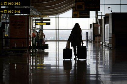 A passenger wheels a suitcase through a deserted arrivals hall at Madrid Barajas airport, in Madrid. Photographer: Paul Hanna/Bloomberg