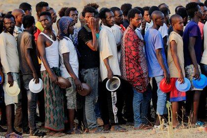 Etíopes que huyeron de la guerra en la región de Tigray, hacen cola para recibir raciones de alimentos en el campamento de Um-Rakoba, en la frontera entre el Sudán y Etiopía, en el estado de Al-Qadarif, Sudán, el 19 de noviembre de 2020. (REUTERS/Mohamed Nureldin Abdallah)