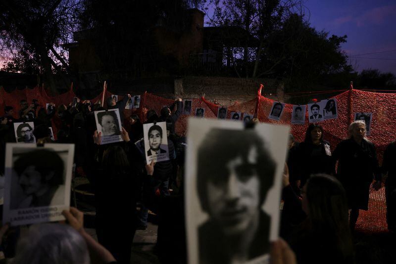 Familiares y activistas sostienen imágenes de personas desaparecidas frente al monumento conmemorativo de Venda Sexy, un antiguo centro de detención y tortura de la dictadura de Augusto Pinochet, en Santiago, Chile, el 29 de agosto de 2023. REUTERS/Ivan Alvarado